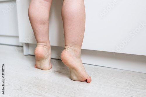 Naked baby's feet close up standing on tiptoes. Kid standing on tiptoes. Development of a healthy child. Little ballerina from childhood