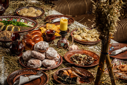 Traditional Christmas table in Ukraine, twelve meatless dishes: kutya, stewed fruit, beet soup, dumplings, fried fish, herring, pickled mushrooms, garlic photo