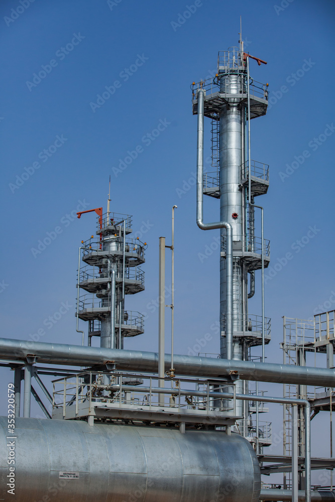 Modern Oil refinery plant. CNPC company. Grey fractional distillation columns, heat exchanger and pipes on blue sky background. 