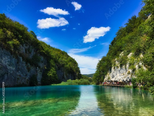 Turquoise lake in Plitvice Lakes National Park in Croatia. Upper Lakes in Plitvicka Jezera with cliff rocks next to lake and beautiful blue sky.