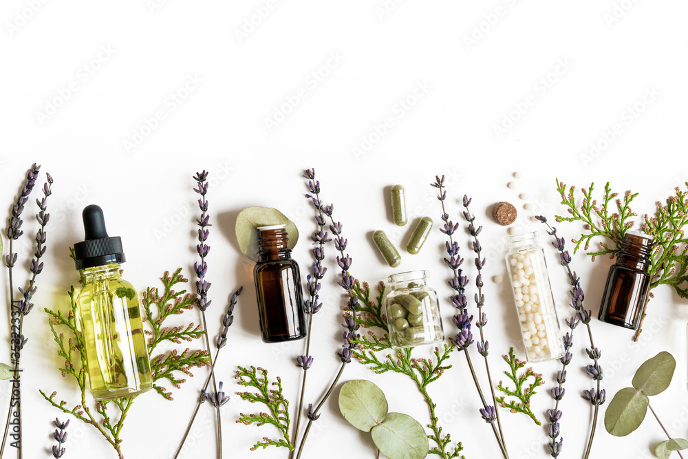 Homeopathy eco alternative medicine concept - classical homeopathy pills, thuja, eucalyptus, lavender essential and aroma oil and healing herbs and on white background. Flatlay. Top view. Copyspace - obrazy, fototapety, plakaty 