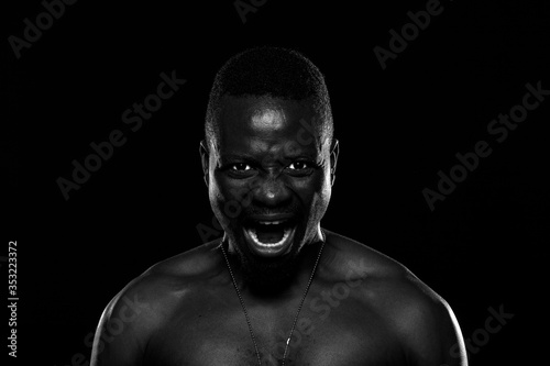 Hombre negro sobre fondo negro con expresión de furia photo