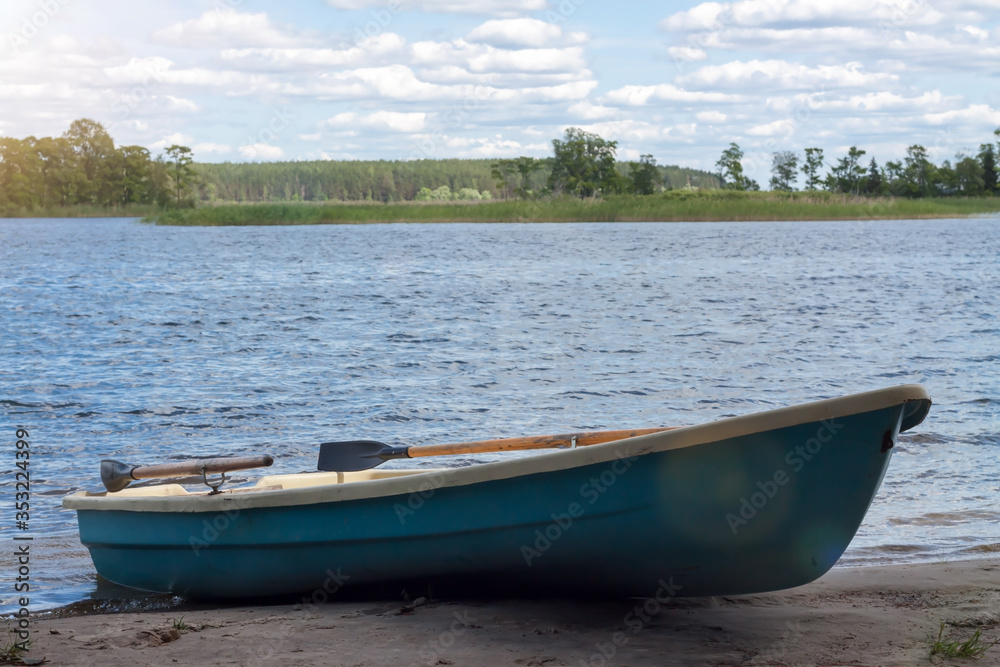 Lonely green rowing boat on lake shore for wild journey