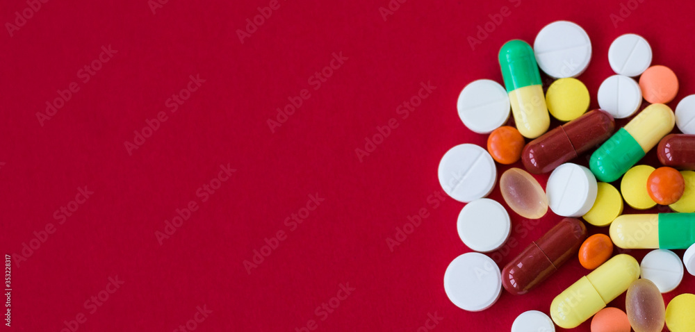 Medical background with pills and capsule on red background.Assorted pharmaceutical medicine pills, tablet. Heap of various assorted medicine tablets and pills different colors. Health care. Top view