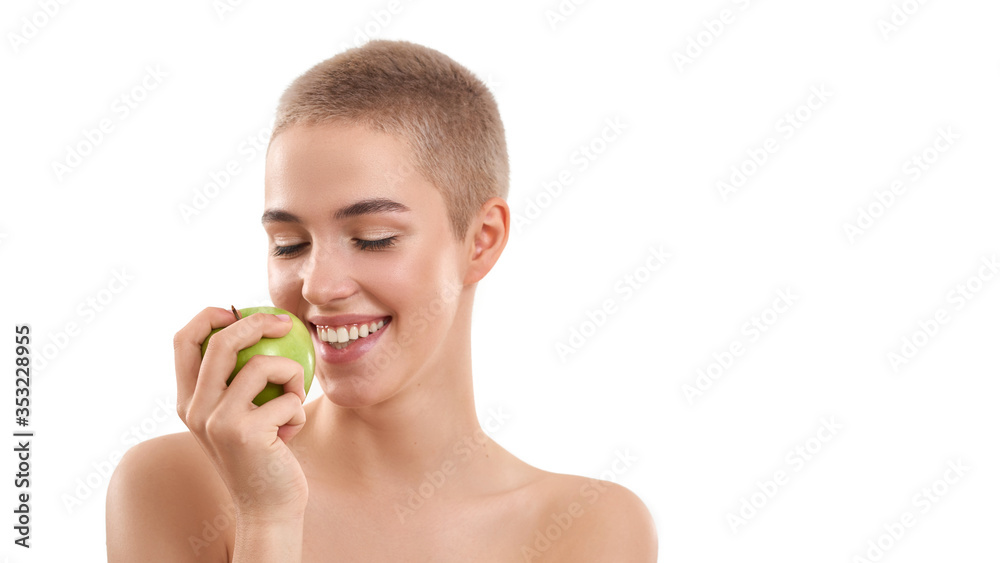Eating healthy food. Portrait of young and happy attractive blonde woman with short haircut holding a fresh apple and smiling while standing against white background Eating healthy food. Portrait of young and happy attractive blonde woman with short haircut holding a fresh apple and smiling while standing against white background