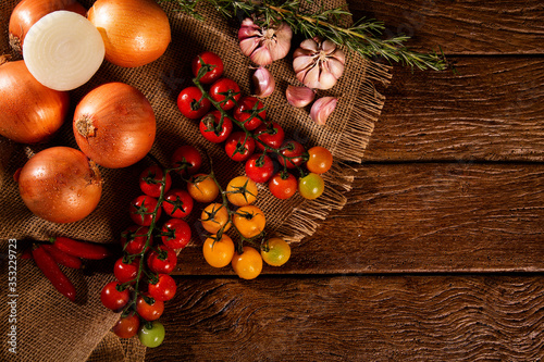 Fototapeta Naklejka Na Ścianę i Meble -  Vegetables on a wooden table top view. Tomato, garlic and onion