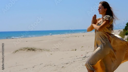 Young beautiful woman in golden long dress standing on sand dunes on Patara beach, Turkey near Mediterranean sea. photo