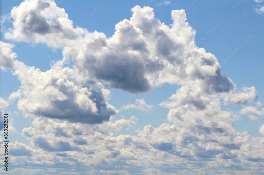 White fluffy clouds on a background of blue sky in summer. The concept of weather and climate. White fluffy clouds on a background of blue sky in summer. The concept of weather and climate.