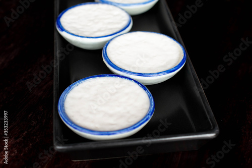 Coconut Milk pudding or Khanom Thuai in black tray on wooden table. photo