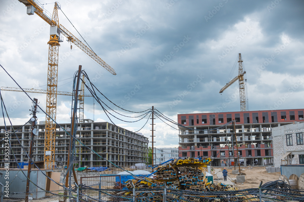 Construction cranes near the unfinished buildings. Construction and developing new districts