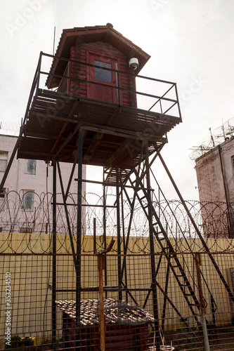 Prison tower and barbed wire fence. Wooden tower with room for guard of prisoners in pre-trial detention center or prison zone © Alex Vog
