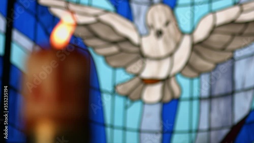 stained glass with figure of the holy spirit and candle or paschal candle