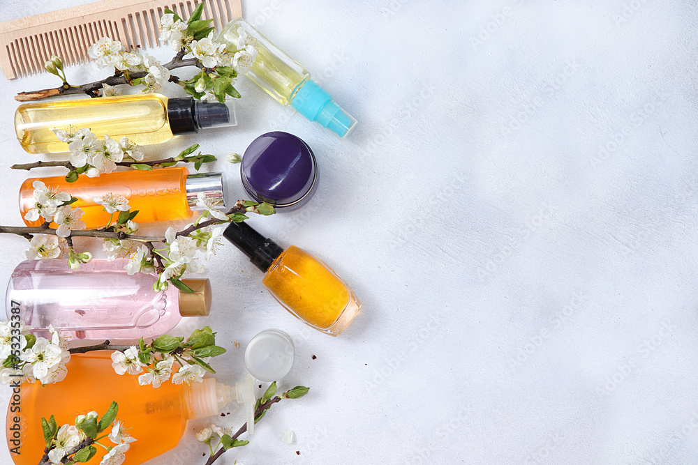 Spa ingredients, a set of cosmetic oils for skin and body care on a gray background with branches of blooming cherry. Shopping concept and modern woman, sale, selective focus Spa ingredients, a set of cosmetic oils for skin and body care on a gray background with branches of blooming cherry. Shopping concept and modern woman, sale, selective focus