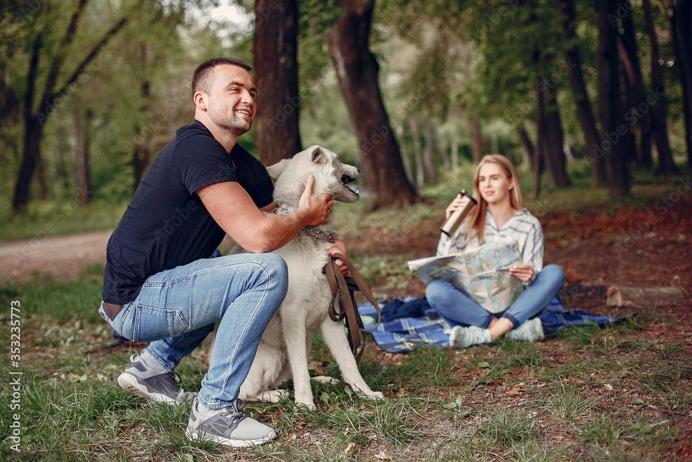 Fototapeta premium Couple in a forest. Pair playing with a cute dog