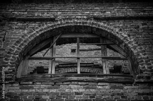 Fototapeta Naklejka Na Ścianę i Meble -  An old wooden window in the wall of a ruined church