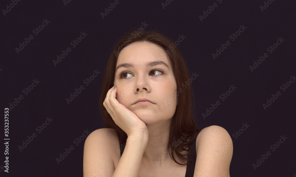 Portrait of a creative young girl looking up while thinking of a new idea or business project against beige background for copy space