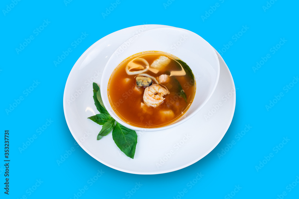 Fish soup with salmon, squid, shrimp, mussels and scallop isolated on blue background Fish soup with salmon, squid, shrimp, mussels and scallop isolated on blue background