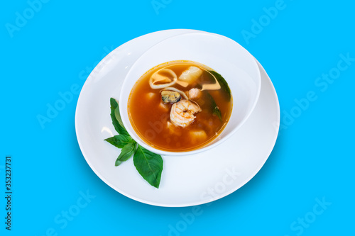 Fish soup with salmon, squid, shrimp, mussels and scallop isolated on blue background