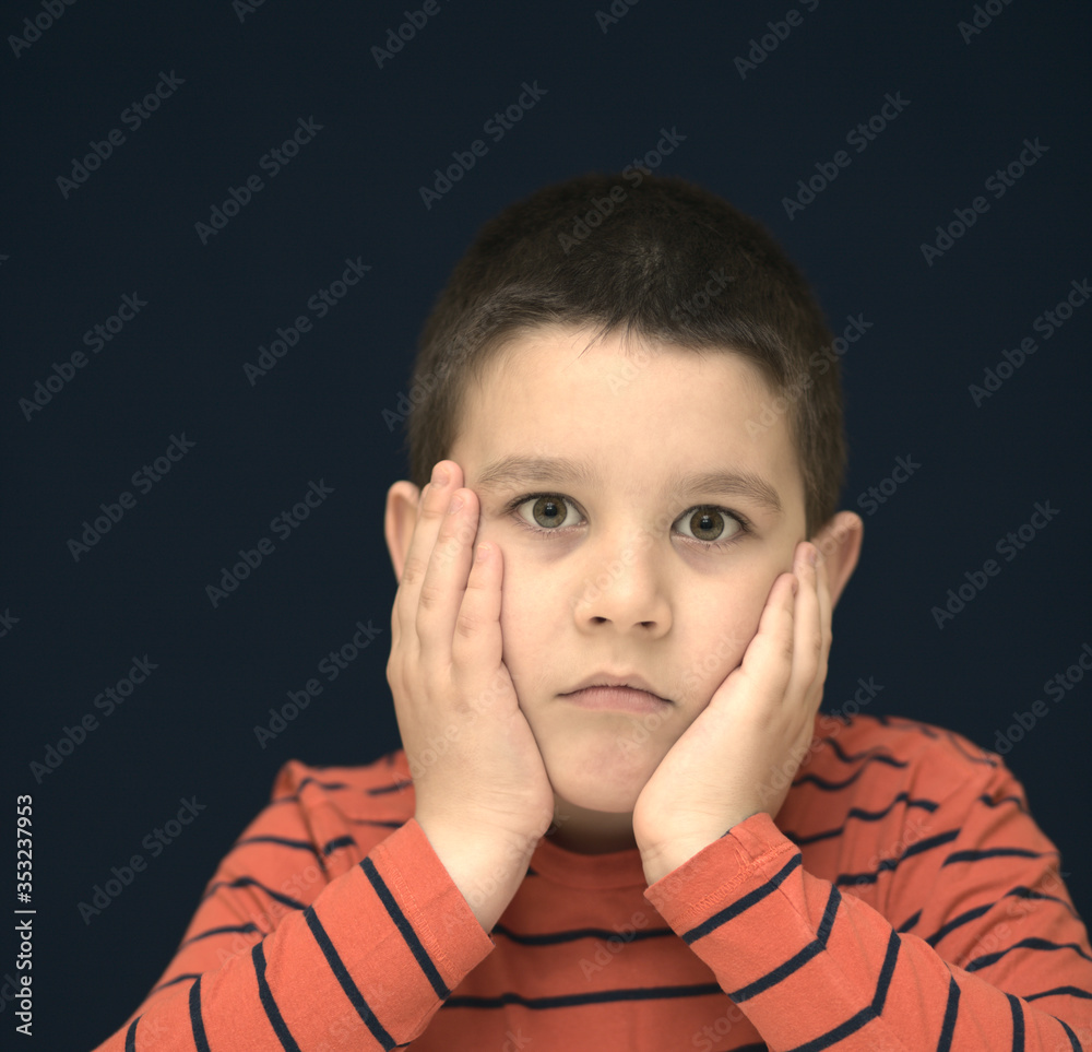 Portrait of a cute boy looking doubtful. Education concept. Dark background