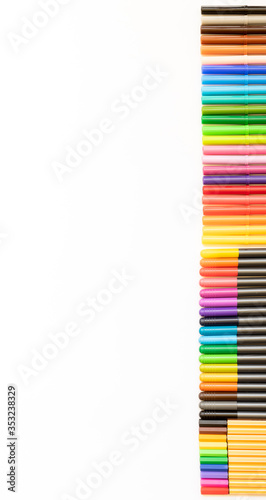 Set of markers of different colors arranged side by side, exactly on the right side of the photo with copy space. White background