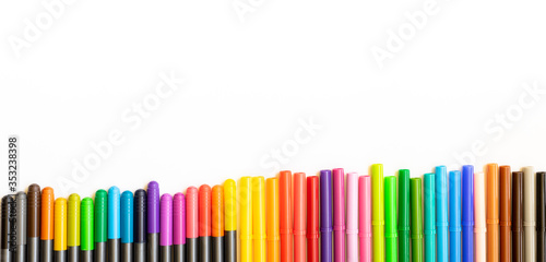Set of different colors markers disposed side by side, exactly at the bottom of the photo with copy space. White background