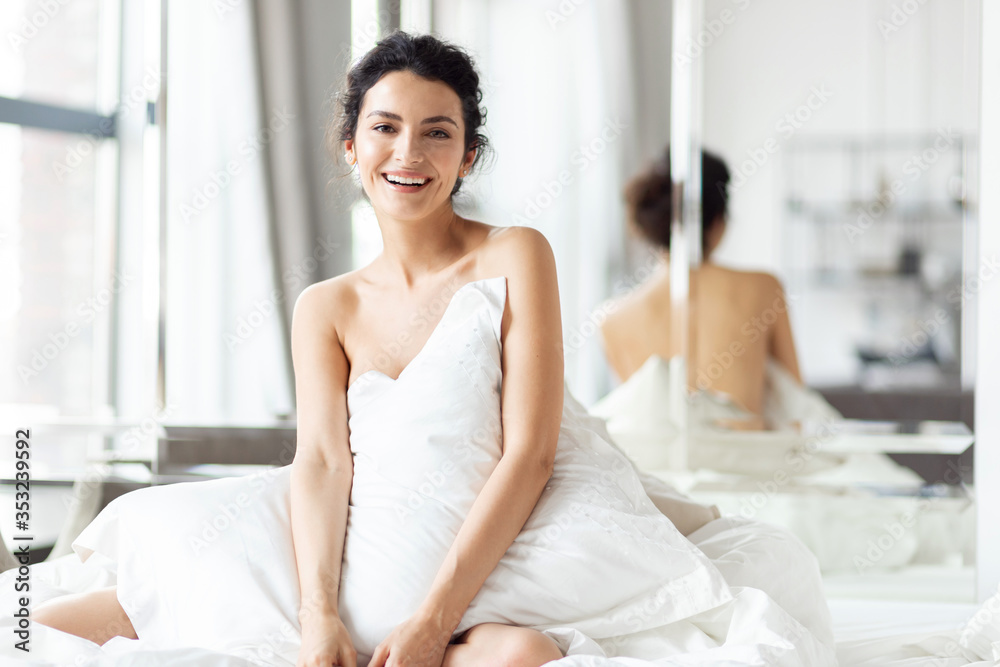 Smiling woman covering body with bedsheet laughing from funny joke. Smiling woman covering body with bedsheet laughing from funny joke.