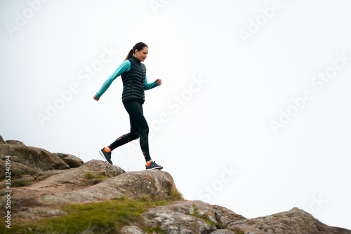 Beautiful Smiling Woman Running on the Mountain Trail at Cold Autumn Evening. Sport and Active Lifestyle.