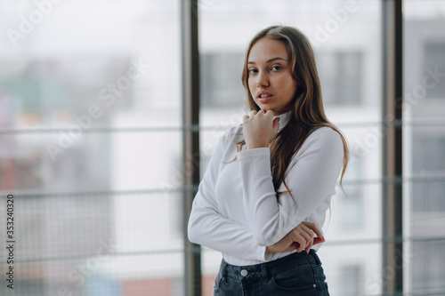 attractive girl on the background of the window shows different emotions and mood. girl on a light background indoors.