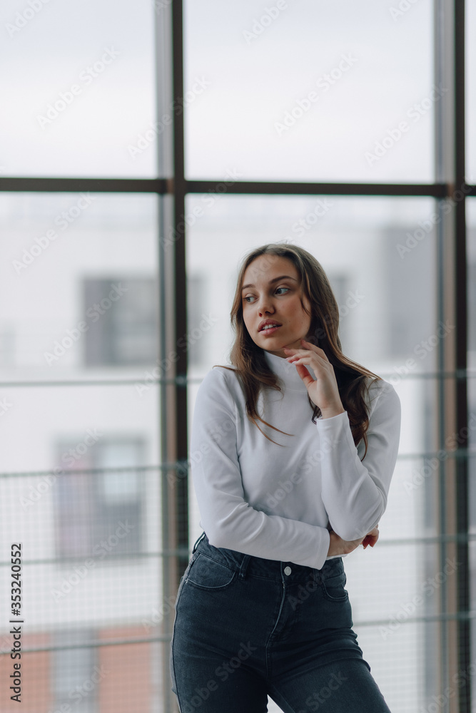attractive girl on the background of the window shows different emotions and mood. girl on a light background indoors. attractive girl on the background of the window shows different emotions and mood. girl on a light background indoors.
