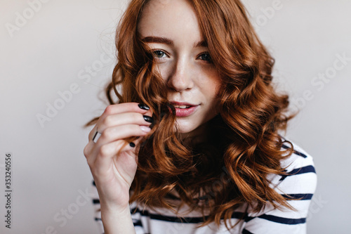 Close-up portrait of blithesome woman with black manicure wears elegant silver ring. Indoor shot of charming ginger girl isolated on light background.