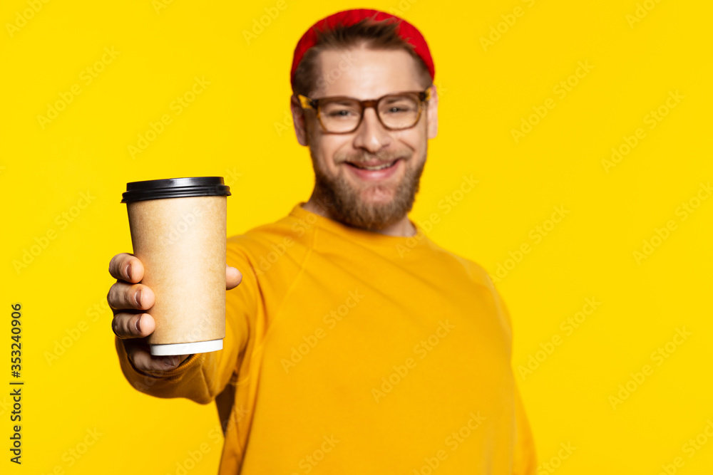 Smiling man giving paper cup of coffee. Focus on paper cup. Smiling man giving paper cup of coffee. Focus on paper cup.
