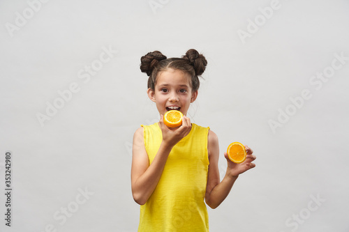 Cute charming girl in yellow t-shirt  laughing merrily and holding half orange.