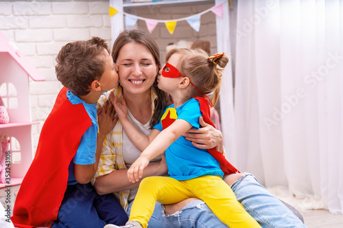 Happy family. A young woman plays with her children in superheroes.