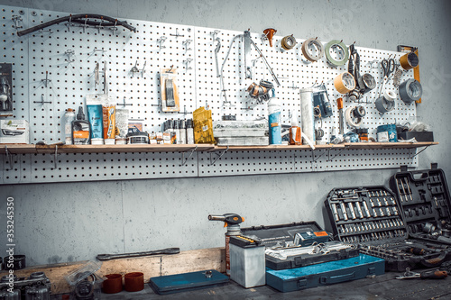 Moto workshop with hand tools. Workbench with sets of keys, screwdrivers, ploskobets, electrical tape, duct tape on the wall. Table with motorcycle parts, vise. Workspace for a joiner, auto mechanic