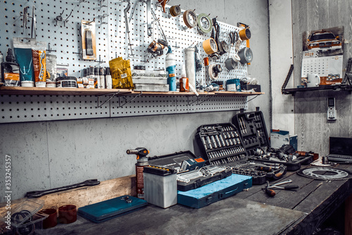 Inside the workshop. Large workbench and tools for working on the table close-up. Workspace for mechanic with wrenches, pliers on a metal wall. Garage for motorcycle repair, car service station. photo