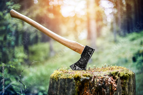 Axe cut in the chopping block, forest green background. Lumber jacks work tool photo