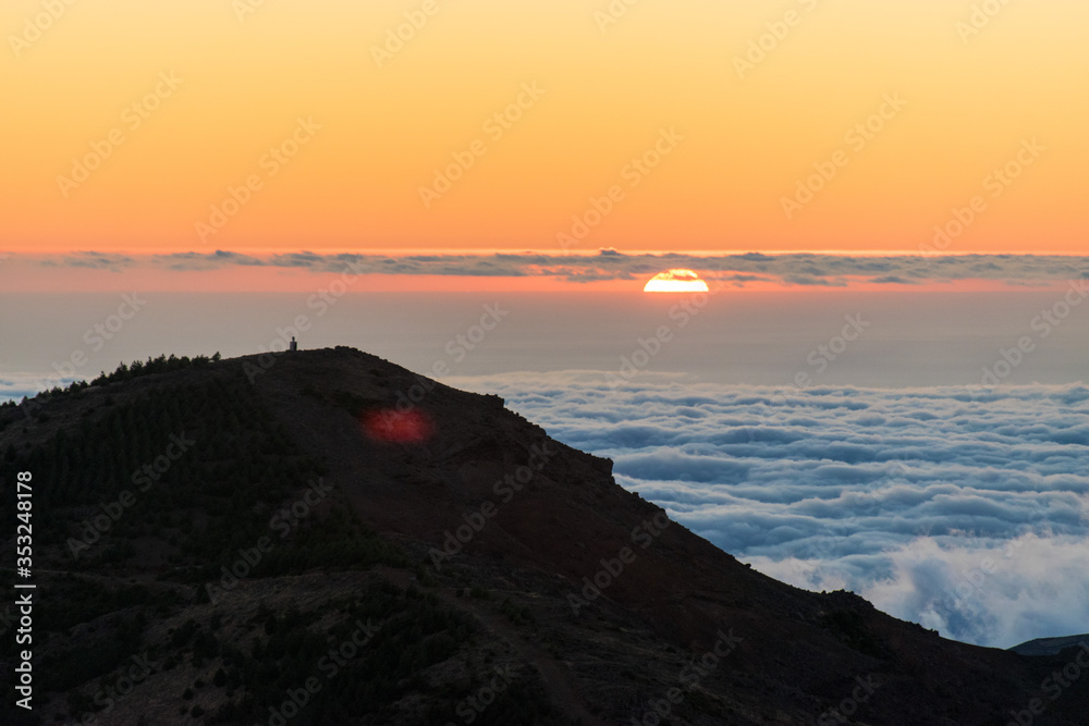 View of Sun setting over the horizon, over clouds and mountains in Madeira