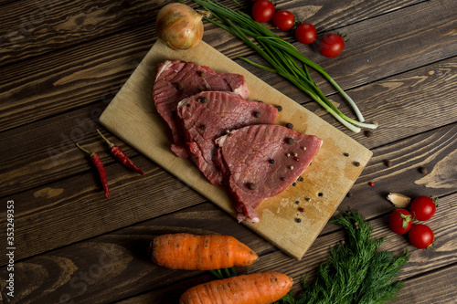 raw meat on a cutting board. beef steak with herbs, cherry tomatoes,