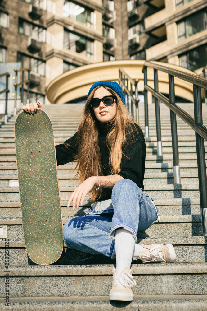 Urban woman with skate. Hipster girl with skateboard in city. Extreme sport  and emotions concept. Alternative lifestyle. Stylish hipster girl holding  skateboard and posing. Street style outfit Stock Photo | Adobe Stock
