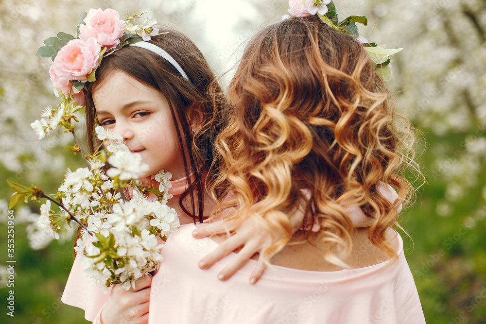Naklejka premium Pretty mother with daughter. Family in a spring park. Woman in a pink dress. Child with a flowers