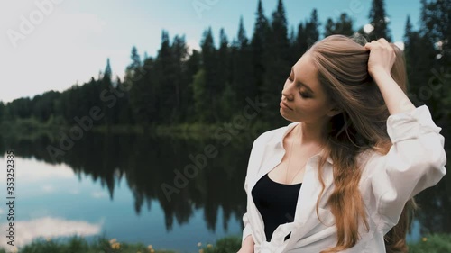 Beautiful young blonde woman sitting and prettier in a park near the lake. Front view