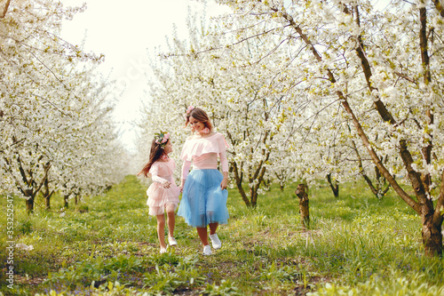 Pretty mother with daughter. Family in a spring park. Woman in a pink dress. Child with a flowers © prostooleh