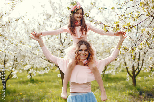 Pretty mother with daughter. Family in a spring park. Woman in a pink dress. Child with a flowers