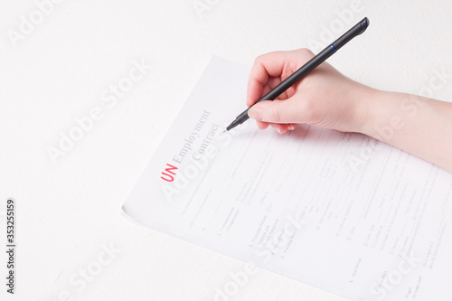 woman signs a black letter of dismissal, fired during the crisis, unemployment concept, white background, copy space