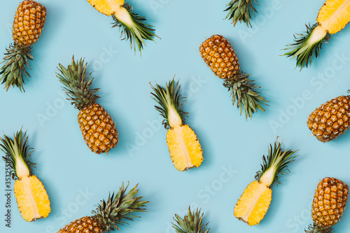 Colorful pattern of pineapples on pastel blue background. Top view. Minimal tropical fruit summer concept.