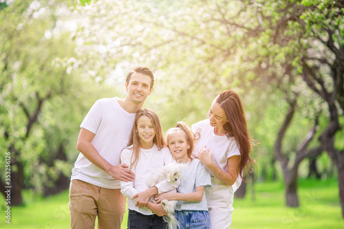 Adorable family in blooming cherry garden on beautiful spring day © travnikovstudio