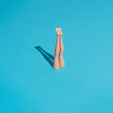 Minimal composition with doll legs and blue background. Sun and sharp shadows. Summer pool or sea diving concept. Vacation and relax inspiration.