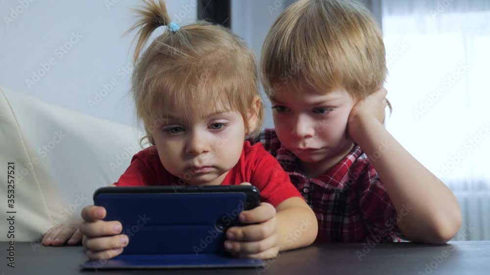 children watch online lifestyle video on a smartphone. little boy and girl brother sister watch online streaming broadcasting cartoons on the phone children watch online lifestyle video on a smartphone. little boy and girl brother sister watch online streaming broadcasting cartoons on the phone