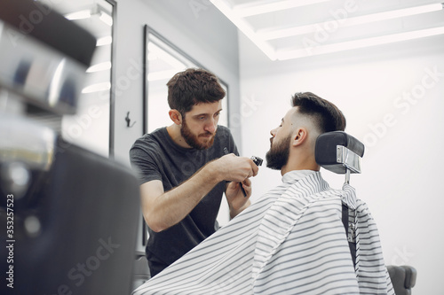 Man with a beard. Hairdresser with a client. Brunette in a barbershop