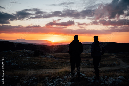 Young backpacker hiker couple enjoying relaxing mountain hike at sunset.Active hiking camping trip vacation.Reconnecting with nature.Climbing up to the mountain top.Mindful walking practice.Wanderlust